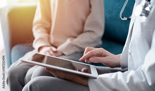 Doctor woman and kid boy patient at home. The pediatrician using tablet computer while filling up medical records, close up. Medicine, healthcare concept