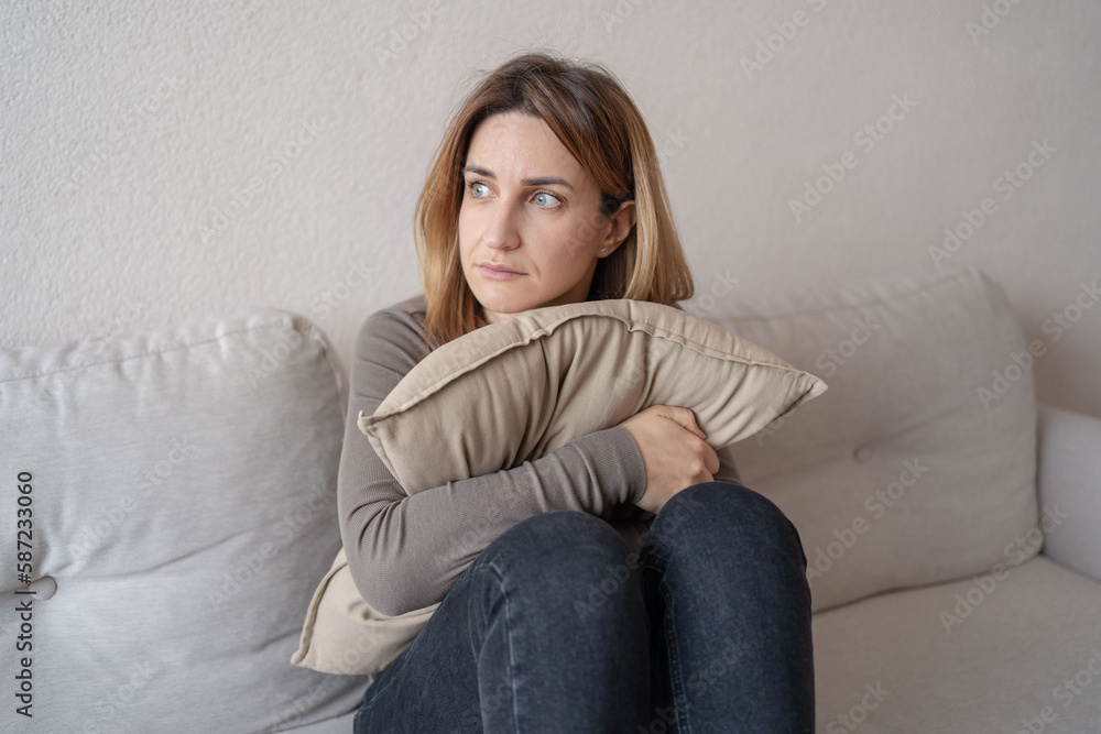 young unhappy sadness girl sitting on sofa hugging pillow. She is feeling not very good due to her sickness and having a headache. Depression, mental health, Sad, tired. young unhappy sadness girl sitting on sofa hugging pillow. She is feeling not very good due to her sickness and having a headache. Depression, mental health, Sad, tired.
