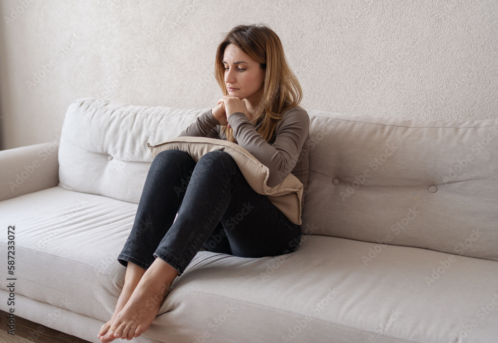 Depression concept. Portrait of sad woman sitting on sofa at home, upset lady suffering melancholy, having bad mood, problems or nervous breakdown, feeling bad and lonely. Depression concept. Portrait of sad woman sitting on sofa at home, upset lady suffering melancholy, having bad mood, problems or nervous breakdown, feeling bad and lonely.