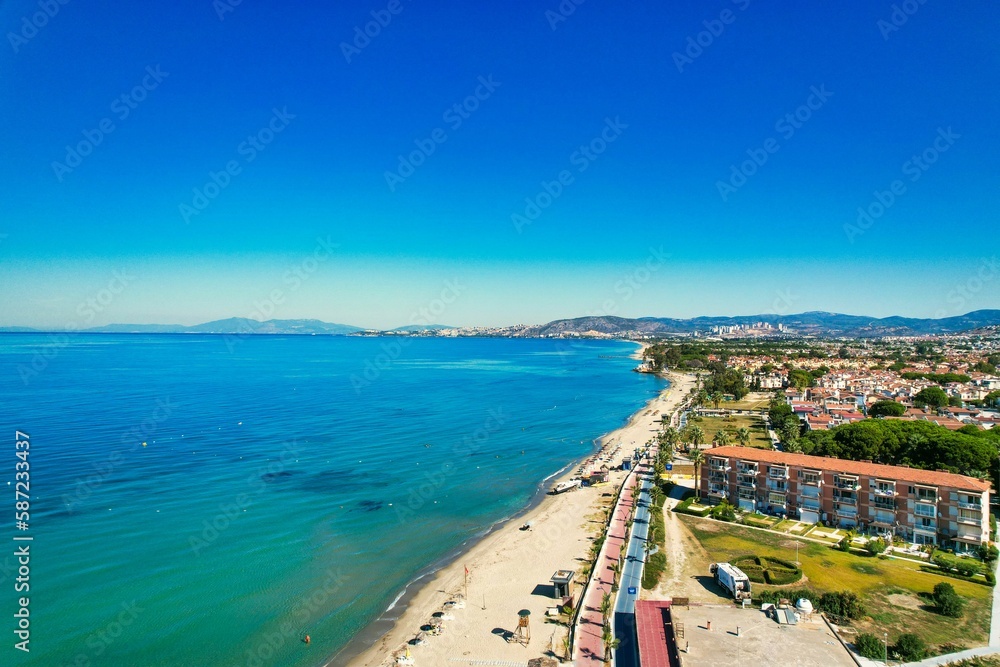 Aerial shot over a sea and a coastal city in Kusadasi under the bright blue sky, Turkey