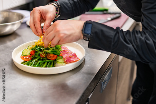 Fototapeta Naklejka Na Ścianę i Meble -  man chef hand cooking tuna slices with fresh vegetables and green beans salad on restaurant kitchen