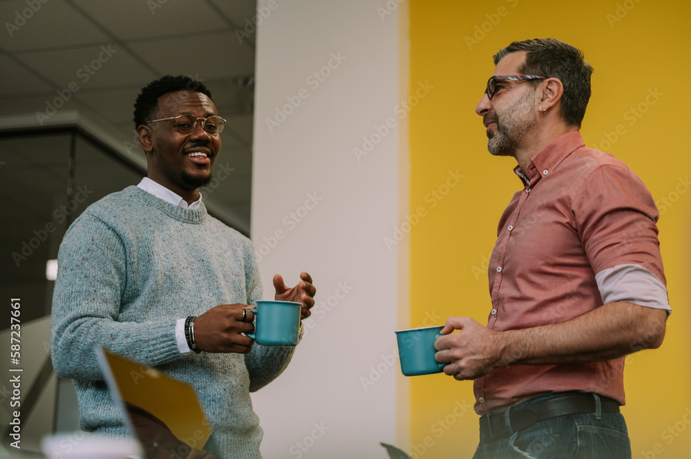 Black male business person explaining something funny to his Caucasian colleague Black male business person explaining something funny to his Caucasian colleague