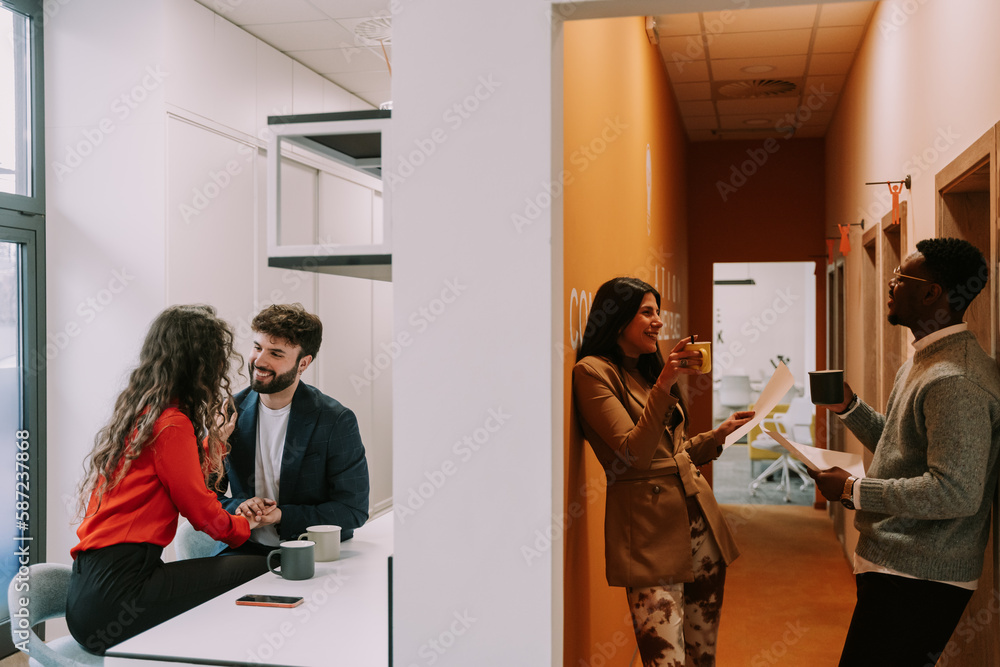 Young Caucasian female people flirting with their multiracial male colleagues at modern office while taking a break from work Young Caucasian female people flirting with their multiracial male colleagues at modern office while taking a break from work