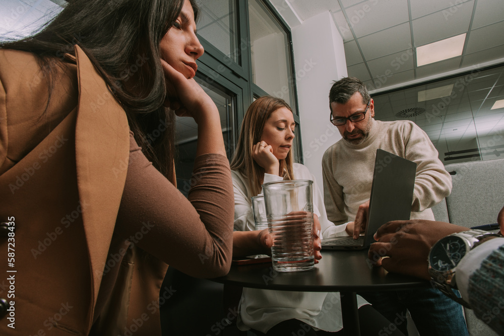 Side view shot of good looking middle-aged business person helping his junior coworkers at the office with their daily tasks at work Side view shot of good looking middle-aged business person helping his junior coworkers at the office with their daily tasks at work
