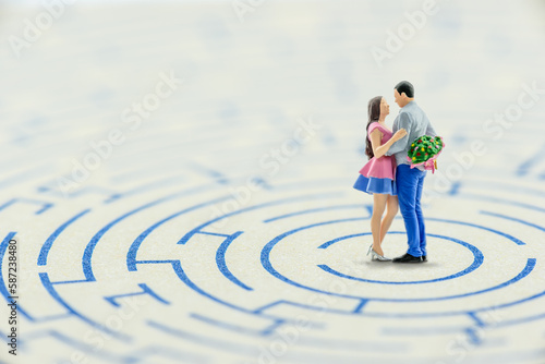 Overcoming obstacles together for married life, newly wed concept : Miniature couple embrace each other in a maze, depicts trouble or problems a new sweetheart will encounter bofore getting married.