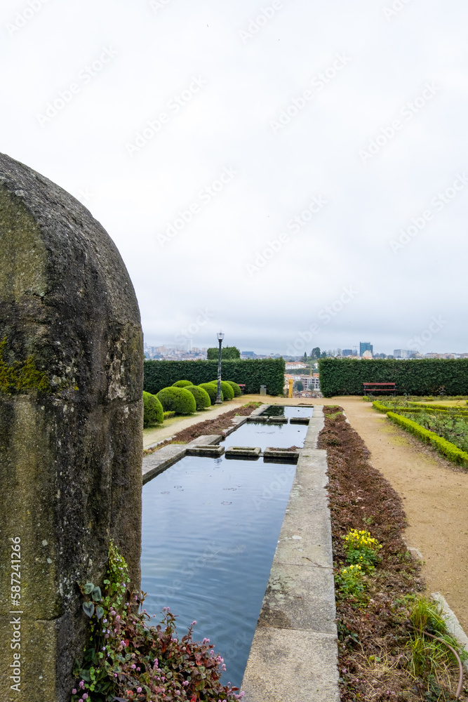 Fuente encontrada en un parque de Oporto con los edificios de la ciudad al fondo desenfocados bajo un cielo nublado.