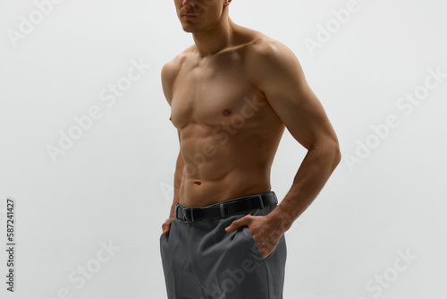 Faceless shot of young muscular man posing shirtless over white studio background. Close up