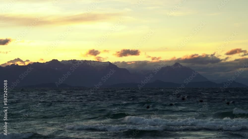 waves crushing ashore on the lake nahuel huapi on a windy day in Patagonia with San Carlos de Bariloche in the background waves crushing ashore on the lake nahuel huapi on a windy day in Patagonia with San Carlos de Bariloche in the background