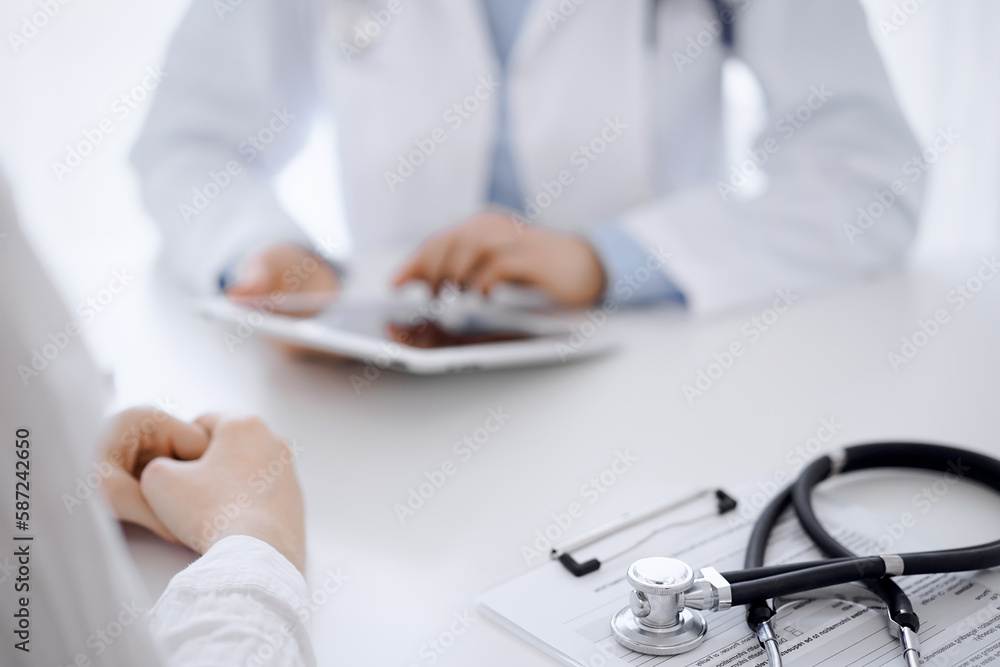 Stethoscope lying on the tablet computer in front of a doctor and patient sitting opposite each other and using tablet computer at the background . Medicine, healthcare concept Stethoscope lying on the tablet computer in front of a doctor and patient sitting opposite each other and using tablet computer at the background . Medicine, healthcare concept