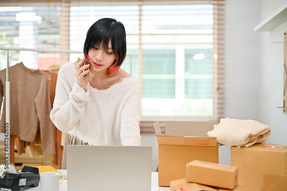 Focused Asian female small business entrepreneur talking on the phone with her supplier Focused Asian female small business entrepreneur talking on the phone with her supplier