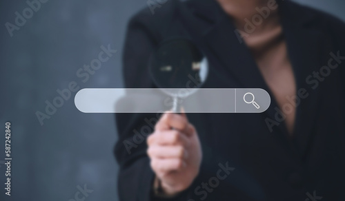 A business man holding magnifier and touch searching bar, technology and internet online concept.