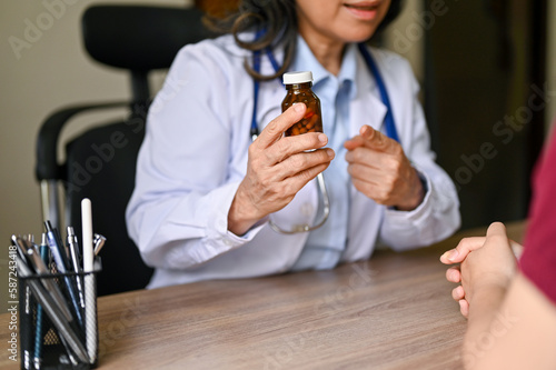 A senior Asian female doctor gives medicine instructions to a patient