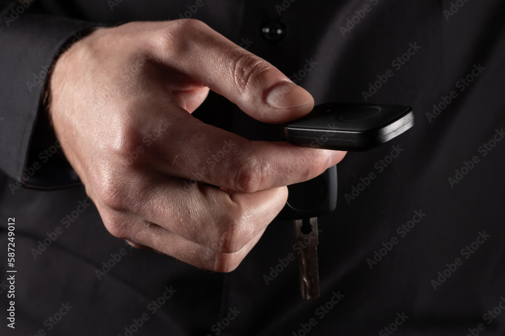 Businessman holding a car key on dark background Businessman holding a car key on dark background