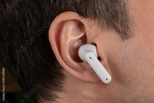 White wireless headphones in ear. Close up photo