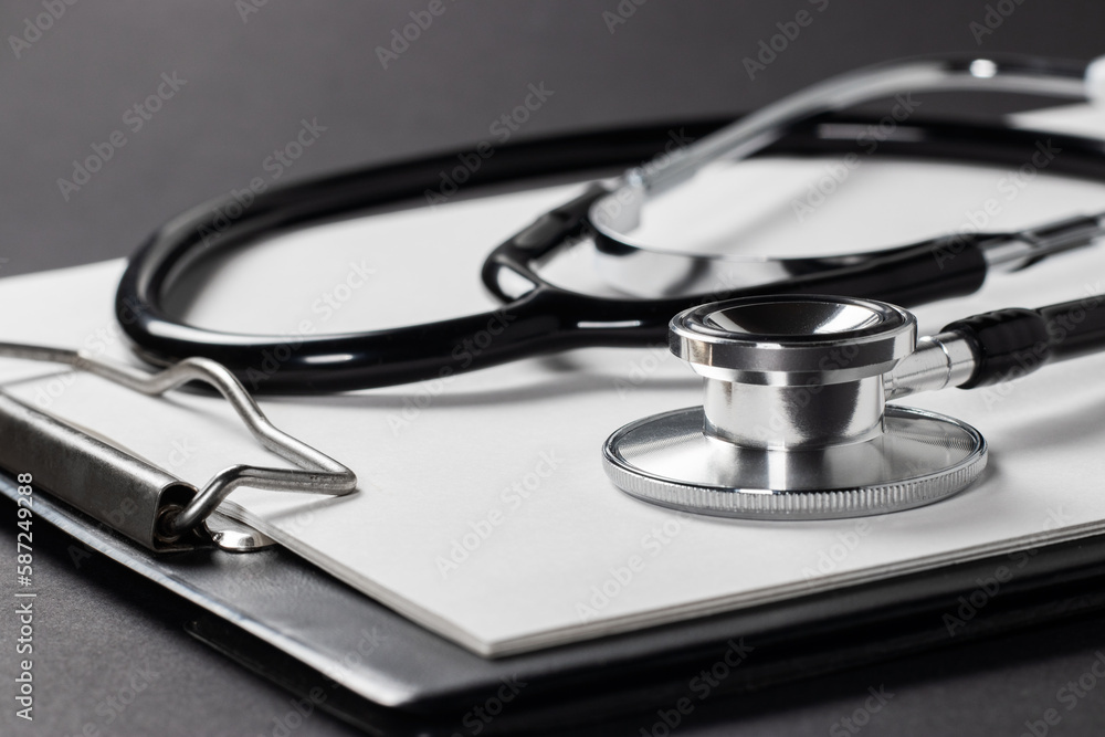 A stethoscope with white paper on it, set against a dark background A stethoscope with white paper on it, set against a dark background