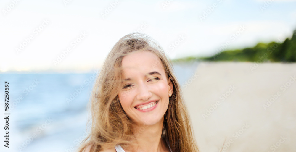 Portrait of a happy smiling woman in free happiness bliss on ocean beach enjoying nature during travel holidays vacation outdoors. View through white blurred flowers Portrait of a happy smiling woman in free happiness bliss on ocean beach enjoying nature during travel holidays vacation outdoors. View through white blurred flowers