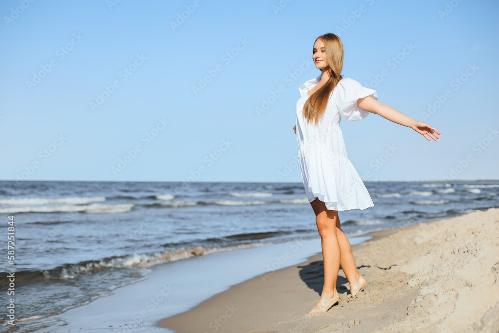 Happy smiling beautiful woman is walking on the ocean beach with open arms Happy smiling beautiful woman is walking on the ocean beach with open arms