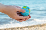 earth day,hands holding a globe against the backdrop of the sea and the beach,environmental conservation