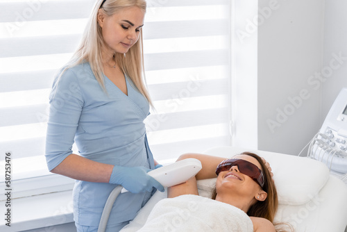 Laser hair removal procedure in a cosmetology beauty salon. Woman cosmetologist removes body hair. Professional aesthetic skin care in a beauty clinic. Smooth and soft skin hands and feet without hair