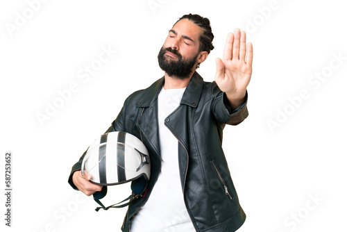 Young man with beard with a motorcycle helmet over isolated chroma key background making stop gesture and disappointed
