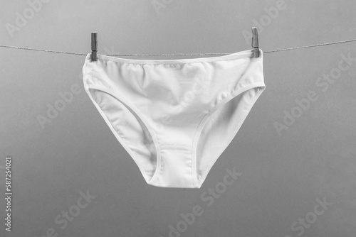 white washed women's panties made of cotton with clothespins hanging on a rope black and white photo
