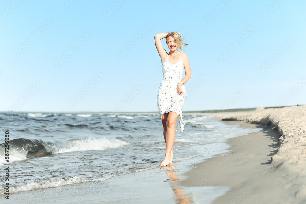 Happy blonde beautiful woman having fun on ocean beach while dancing in waves Happy blonde beautiful woman having fun on ocean beach while dancing in waves