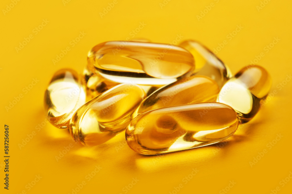 Fish oil capsules with omega 3 and vitamin D on yellow background Fish oil capsules with omega 3 and vitamin D on yellow background