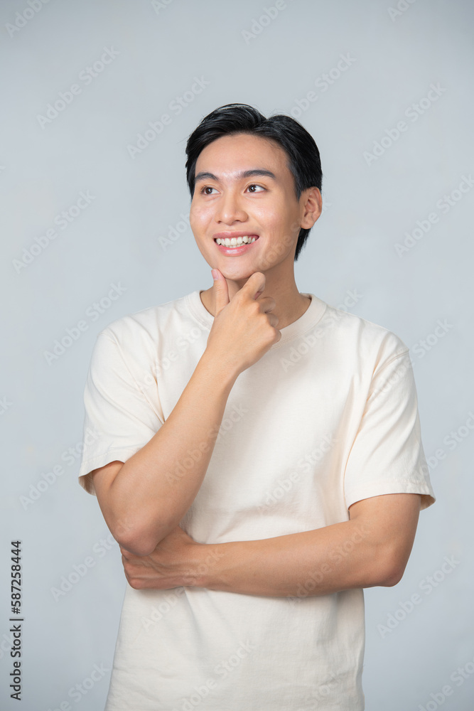 Asian man looking at camera with his hand on chin showing happy face Asian man looking at camera with his hand on chin showing happy face