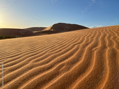 Dunes in the Sahara desert, Merzouga desert, grains of sand forming small waves on the dunes, panoramic view. Setting sun. Morocco 