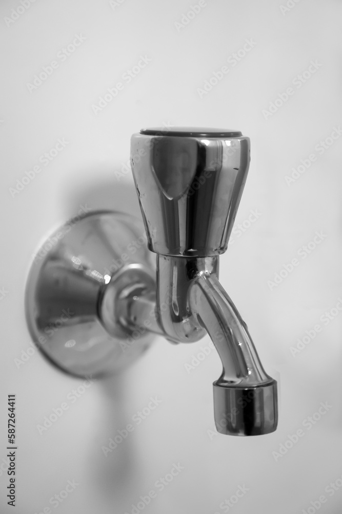 Nahaufnahme eines Wasserhahn an einer weißen Wand. Nahaufnahme eines Wasserhahn an einer weißen Wand.