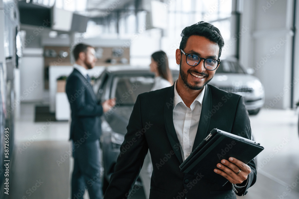 Using graphic tablet. Three people are working together in the car showroom Using graphic tablet. Three people are working together in the car showroom