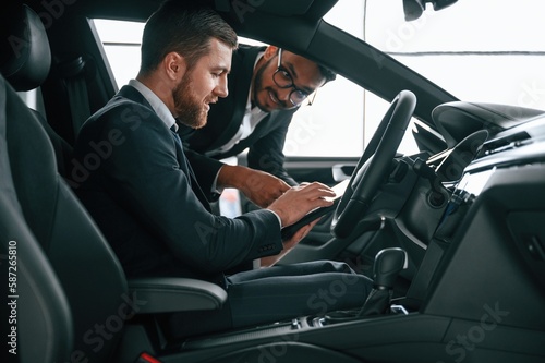 Side view. Man showing automobile interior to the customer