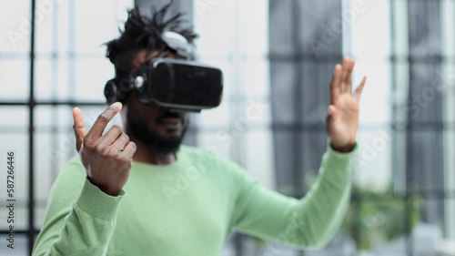 Cool handsome african american man put on virtual reality goggles for the first time in the office.