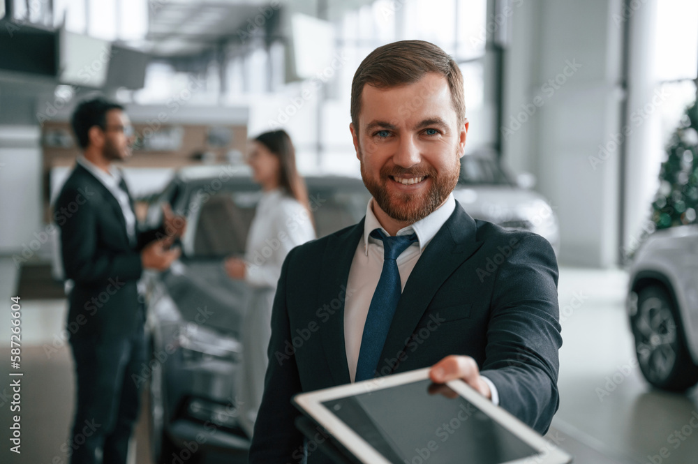 Using graphic tablet. Three people are working together in the car showroom