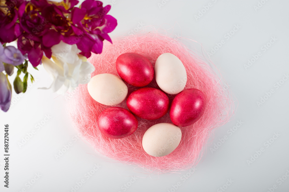 easter pink eggs on a white background with a bouquet of spring freesias. Top view. easter pink eggs on a white background with a bouquet of spring freesias. Top view.