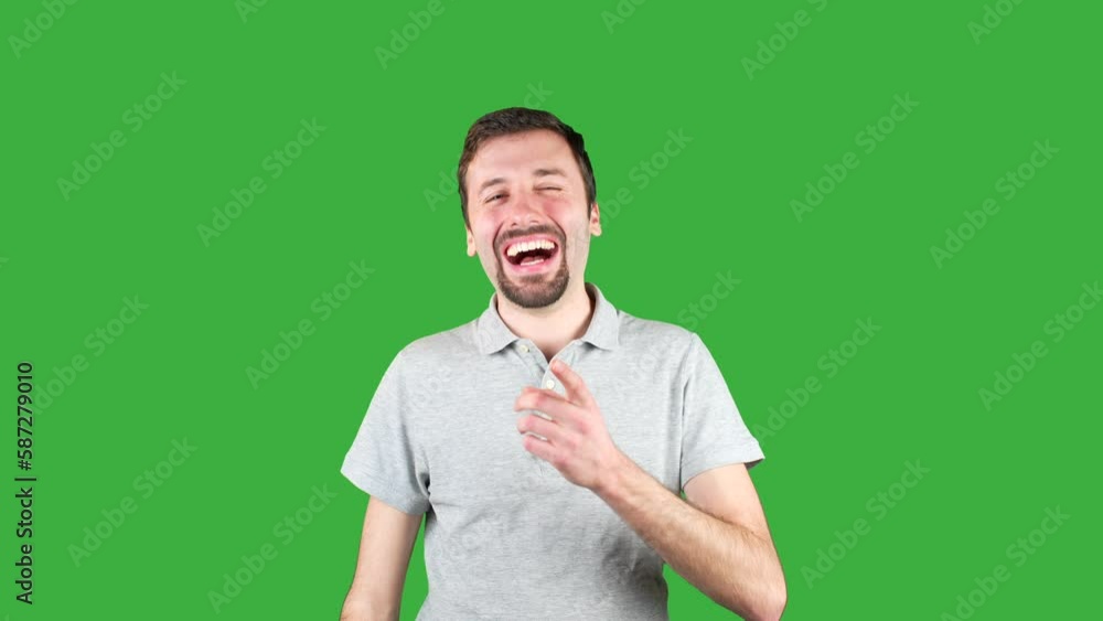 Close-up shot of a man bursting into laughter on a green screen ...
