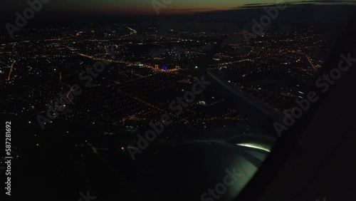 View from the plane window of the lights of a glowing city at night. Flight over the metropolis at night on an airplane view from the wing window. Aircraft takeoff and climb