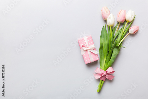 Fototapeta Naklejka Na Ścianę i Meble -  Pink tulips flowers and gift or present box on colored table background. Mothers Day, Birthday, Womens Day, celebration concept. Space for text top view