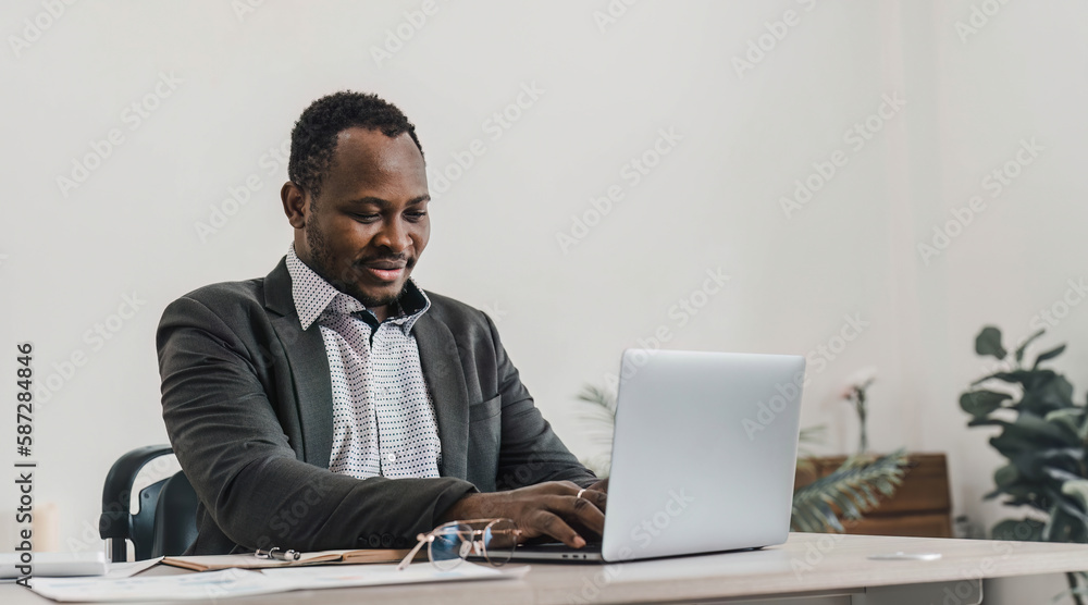 Focused african american businessman working with laptop documents in office holding papers preparing report analyzing work results, black male analyst doing paperwork at workplace using computer Focused african american businessman working with laptop documents in office holding papers preparing report analyzing work results, black male analyst doing paperwork at workplace using computer