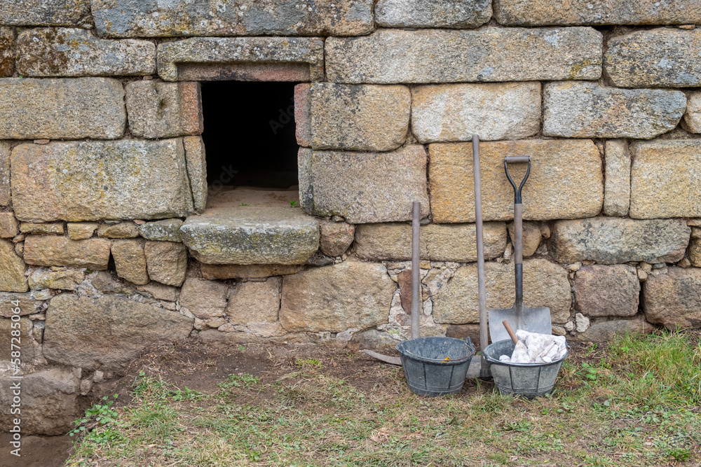tools next to an ancient granite stone wall in an archaeological excavation tools next to an ancient granite stone wall in an archaeological excavation