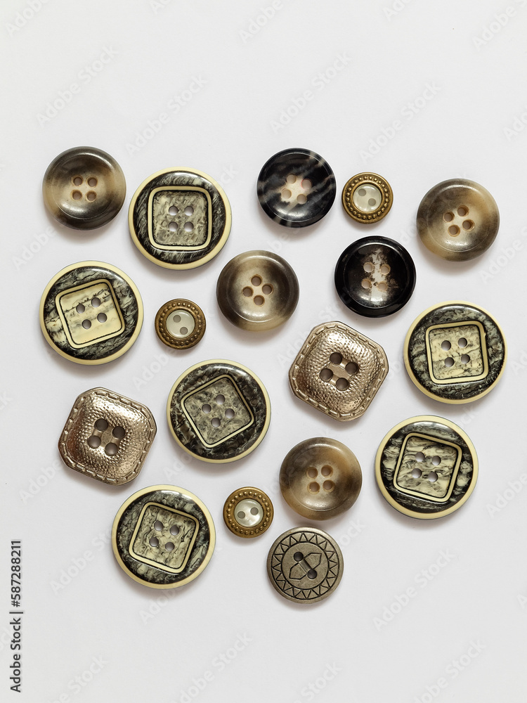 Collection of different grey plastic buttons on a white background. Sewing tools. Top view. Collection of different grey plastic buttons on a white background. Sewing tools. Top view.