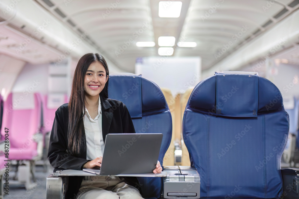 Female passenger sitting on plane while working on laptop computer with simulated space using on board wireless connection