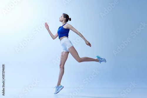 Fototapeta Naklejka Na Ścianę i Meble -  Active sportive young girl in comfortable sportswear training, doing workout exercises against light blue studio background. Concept of sport, healthy and active lifestyle, beauty, fitness