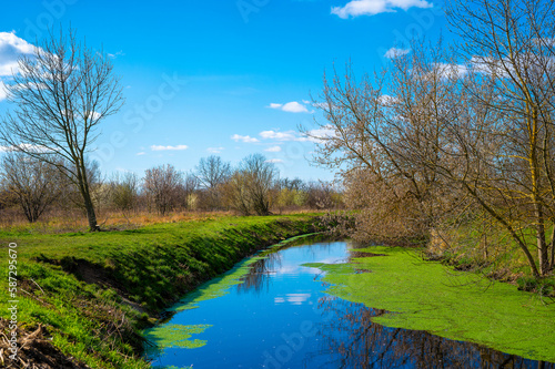 Blue and cloudy sky over a little creek in the surrounding countryside of Berlin, Germany.