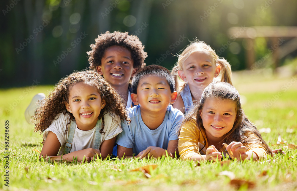 © Nina Lawrenson/peopleimages.com - Portrait, smile and children lying on grass in nature on vacation outdoor for learning. Kids, diversity and happiness of group enjoying summer holiday at park or garden, bonding or relaxing together.