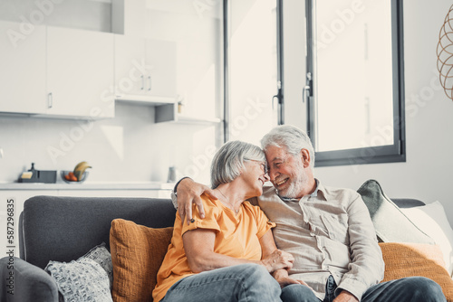 Happy laughing older married couple talking, laughing, standing in home interior together, hugging with love, enjoying close relationships, trust, support, care, feeling joy, tenderness.