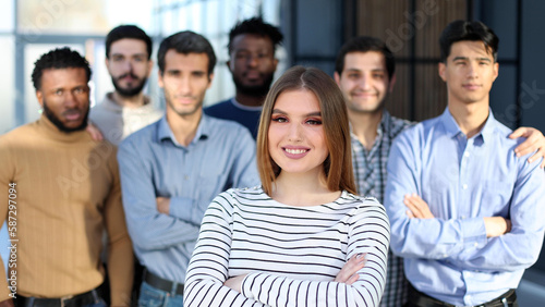 young woman posing for the camera in front of her team in the office