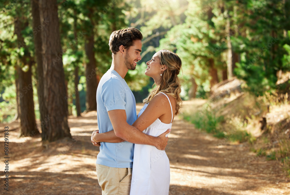 Happy couple, hug and outdoor forest road of young people showing love for engagement announcement. Woods, trees and care of a woman and man together on holiday in nature with a smile and happiness Happy couple, hug and outdoor forest road of young people showing love for engagement announcement. Woods, trees and care of a woman and man together on holiday in nature with a smile and happiness