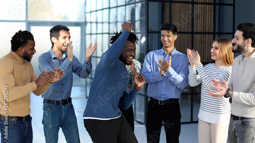 happy excited millennial employees shouting for joy, raising hands for emotional high fives.