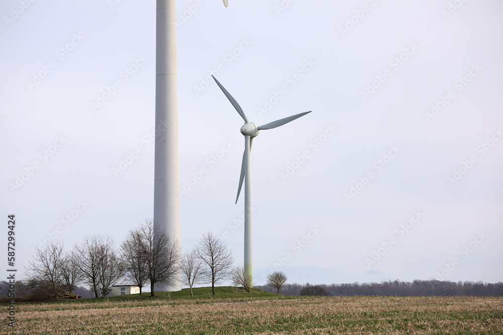 Fototapeta premium Single windmill with a tower of another windmill in the front in rural landscape with cloudy sky